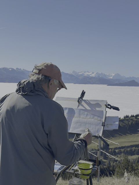 A man does art while overlooking the Swiss Alps on the Mad About Art! trip.